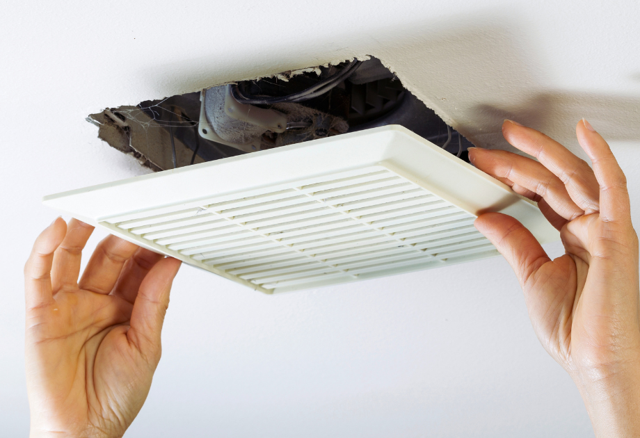zoomed in image of someone placing a white, square vent on the ceiling.  Only the persons hands are visible